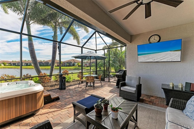 view of patio featuring a hot tub, a water view, ceiling fan, glass enclosure, and area for grilling