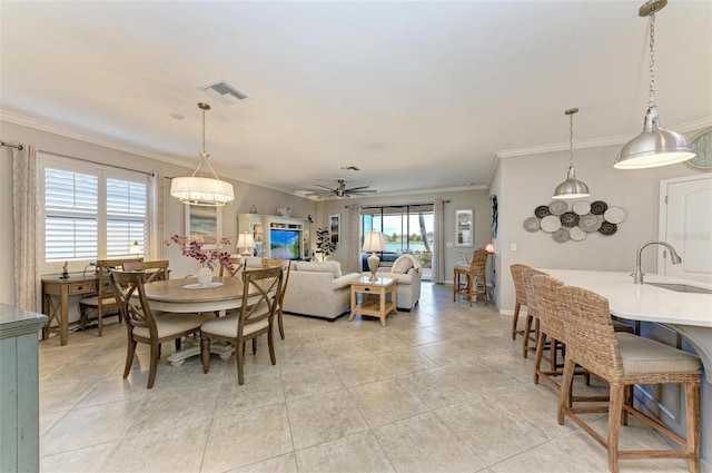 tiled dining area featuring sink, ceiling fan, and crown molding