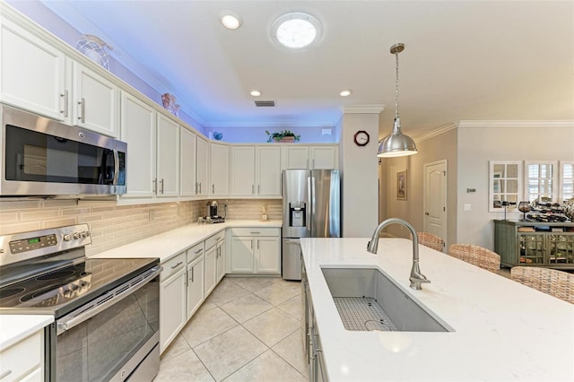 kitchen featuring appliances with stainless steel finishes, hanging light fixtures, sink, white cabinetry, and tasteful backsplash