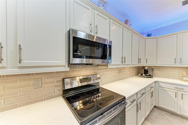 kitchen featuring light stone countertops, stainless steel appliances, light tile patterned floors, backsplash, and white cabinets