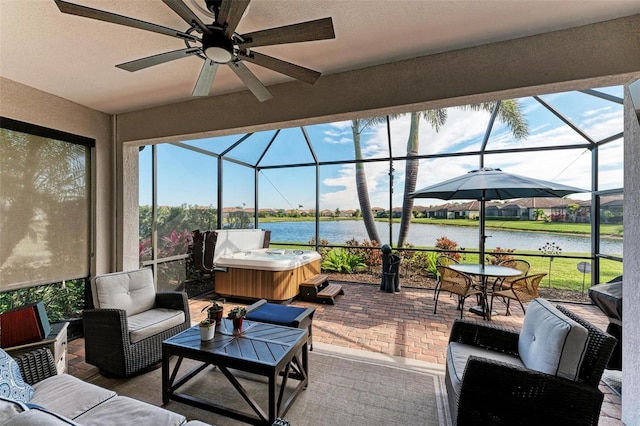 view of patio / terrace featuring a water view, ceiling fan, glass enclosure, a hot tub, and outdoor lounge area