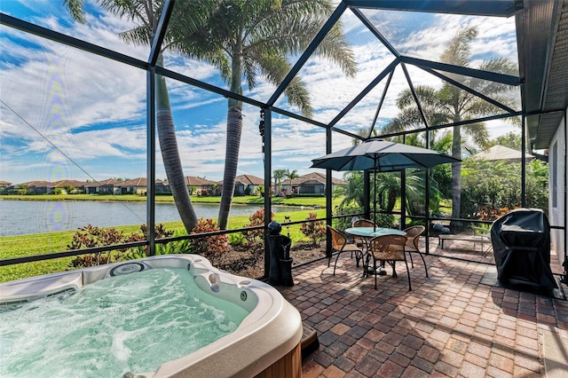 view of patio / terrace featuring area for grilling, a lanai, a hot tub, and a water view