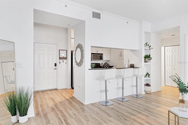 kitchen featuring light hardwood / wood-style floors, white cabinetry, and crown molding