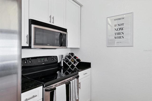 kitchen featuring white cabinets, appliances with stainless steel finishes, and dark stone countertops