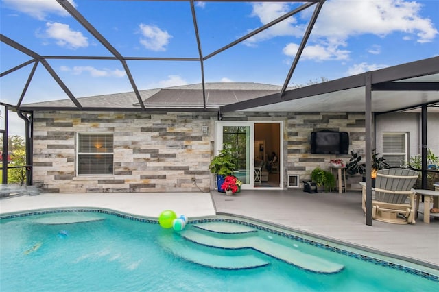 view of pool with glass enclosure and a patio