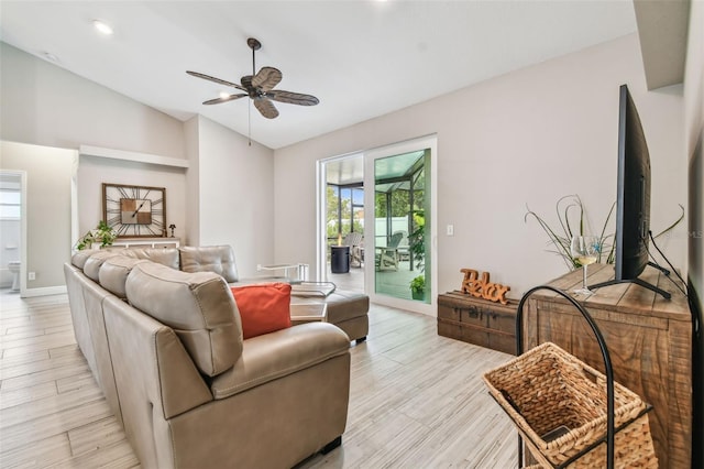 living room with light hardwood / wood-style floors, ceiling fan, and vaulted ceiling