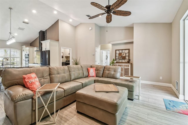 living room with ceiling fan, light wood-type flooring, sink, and high vaulted ceiling