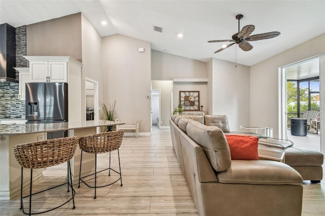 living room with ceiling fan, light wood-type flooring, and lofted ceiling