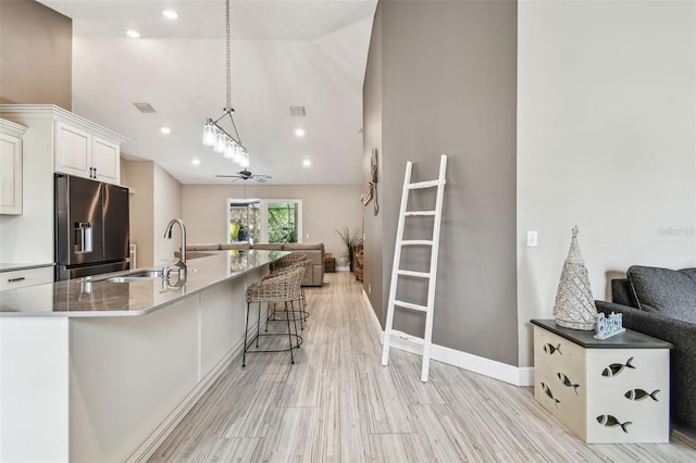 kitchen with stainless steel refrigerator with ice dispenser, ceiling fan, light wood-type flooring, hanging light fixtures, and sink