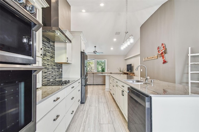 kitchen with appliances with stainless steel finishes, wall chimney exhaust hood, white cabinetry, decorative backsplash, and sink