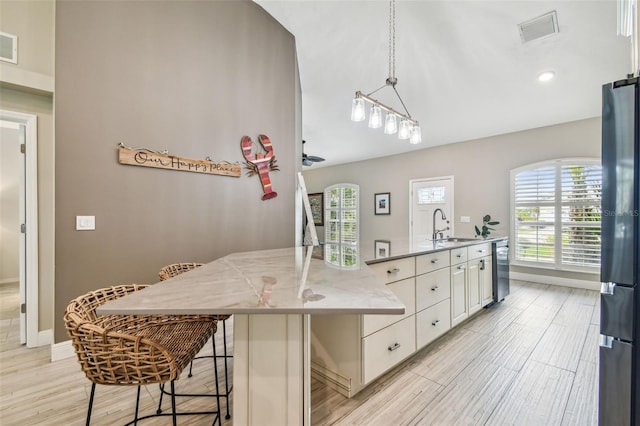 kitchen with hanging light fixtures, appliances with stainless steel finishes, sink, and a center island with sink