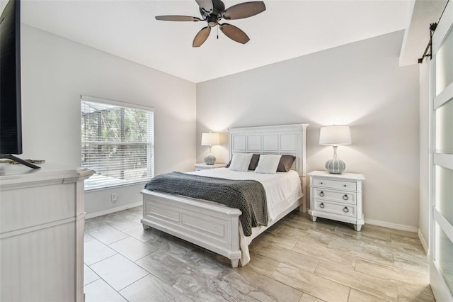 bedroom with ceiling fan and a barn door