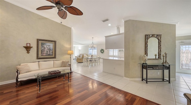 living room with light tile patterned floors, ceiling fan with notable chandelier, and ornamental molding