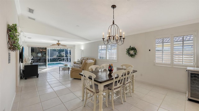 dining area featuring ceiling fan with notable chandelier, lofted ceiling, crown molding, and light tile patterned floors