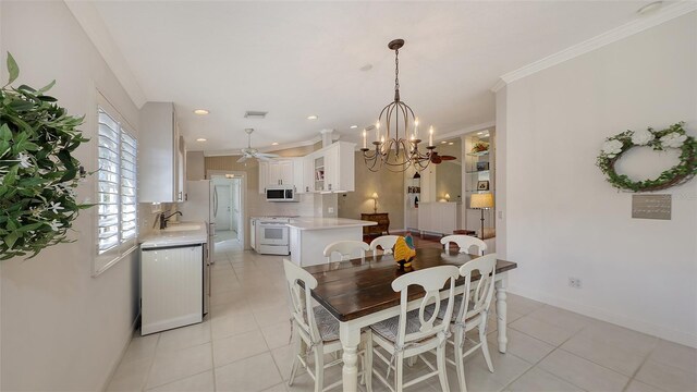 dining room with light tile patterned floors, ceiling fan with notable chandelier, crown molding, and sink