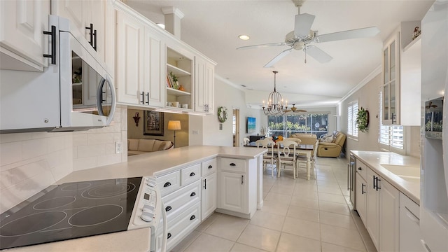 kitchen with hanging light fixtures, white cabinets, kitchen peninsula, crown molding, and light tile patterned flooring