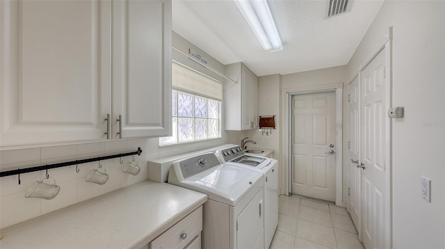 washroom with cabinets, a textured ceiling, washer and clothes dryer, sink, and light tile patterned flooring