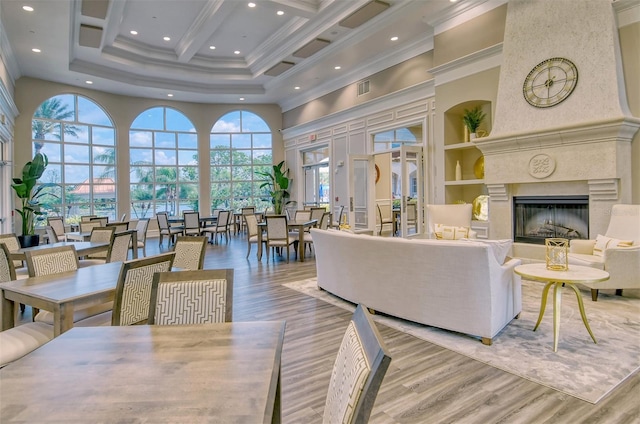 living room featuring hardwood / wood-style flooring, ornamental molding, a fireplace, and a high ceiling