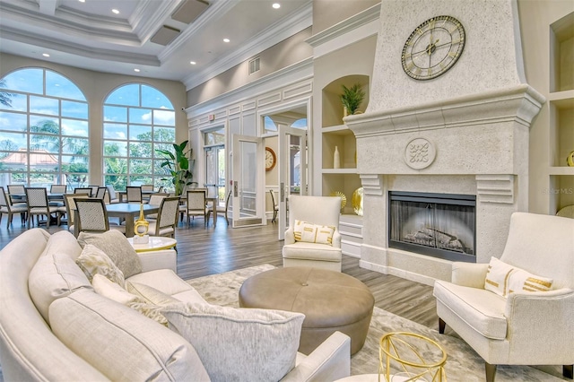 living room with a high end fireplace, a high ceiling, crown molding, built in features, and wood-type flooring