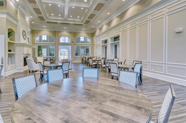 dining space featuring built in shelves, coffered ceiling, a high ceiling, beamed ceiling, and crown molding