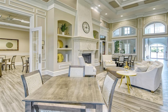 dining space featuring built in shelves, light hardwood / wood-style floors, ornamental molding, and a premium fireplace