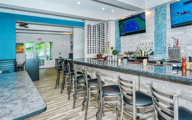 bar with ceiling fan and stone countertops