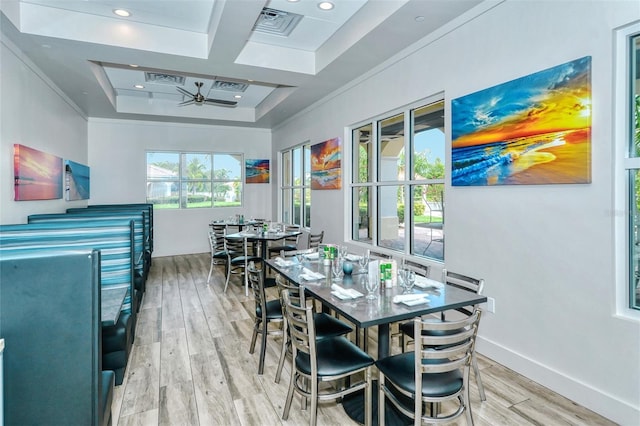 dining room with ceiling fan, light hardwood / wood-style floors, ornamental molding, and a tray ceiling