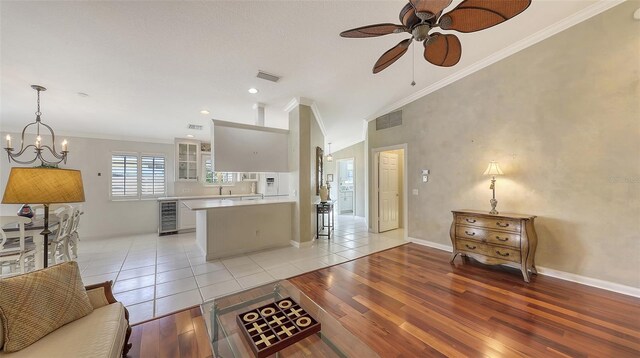 7575 Quinto Dr, Sarasota, FL 34238 - kitchen with crown molding, wine cooler, light hardwood / wood-style floors, white cabinets, and ceiling fan with notable chandelier