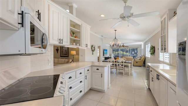 7575 Quinto Dr, Sarasota, FL 34238 - kitchen with decorative light fixtures, white cabinets, light tile patterned floors, kitchen peninsula, and crown molding