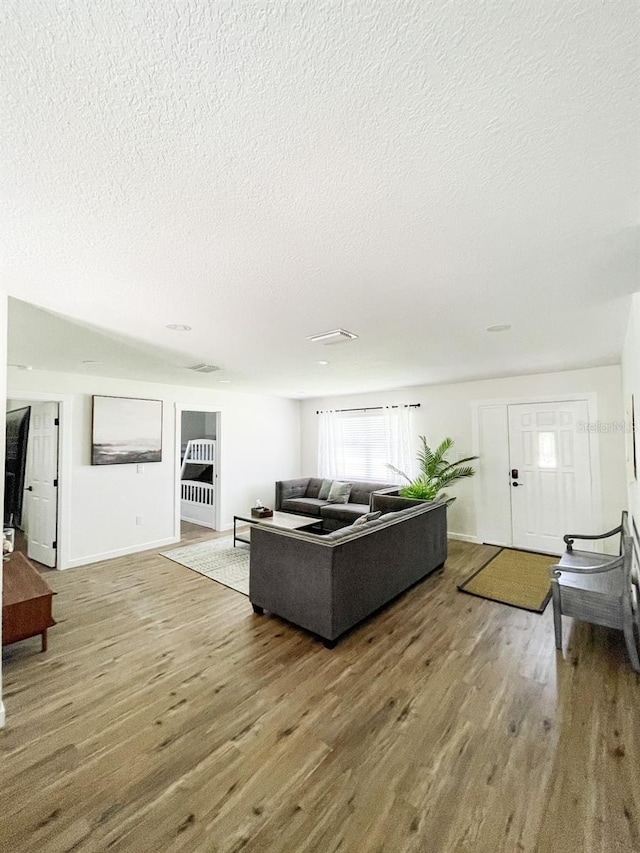 living room featuring wood-type flooring and a textured ceiling