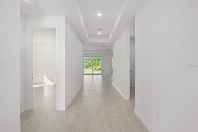 hallway featuring a raised ceiling and light tile patterned floors