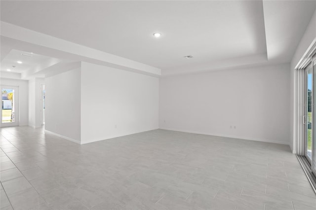 tiled empty room featuring a tray ceiling