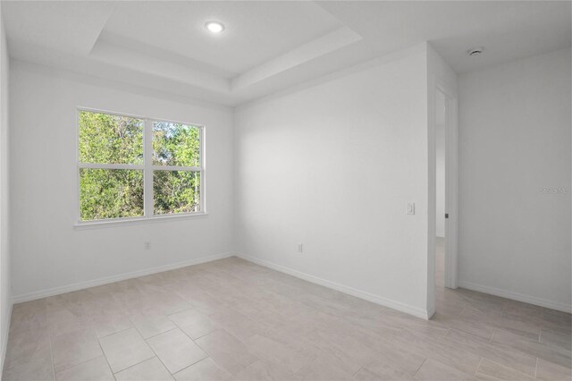 tiled spare room featuring a tray ceiling