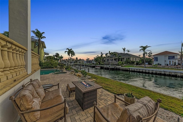 patio terrace at dusk with a water view and an outdoor fire pit