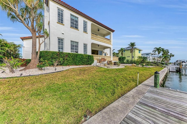 exterior space featuring a water view, a balcony, and a yard