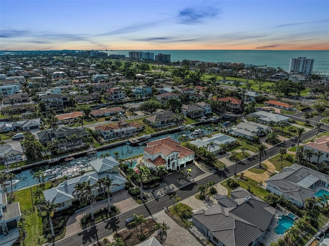 aerial view at dusk featuring a water view