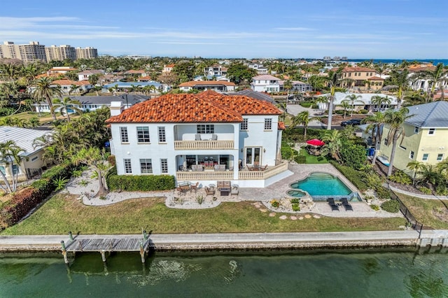 back of property with a water view, a balcony, and a patio area