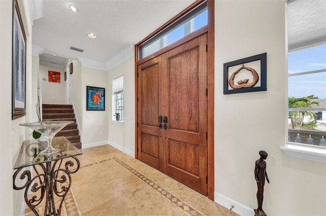 tiled entryway with ornamental molding and a healthy amount of sunlight