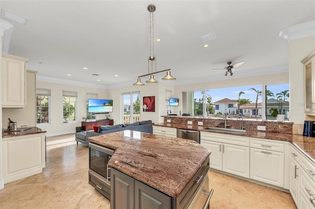 kitchen featuring sink, white cabinetry, a center island, hanging light fixtures, and appliances with stainless steel finishes