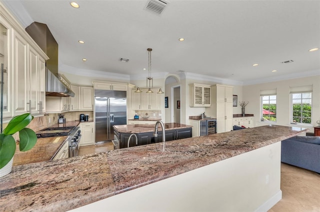 kitchen with tasteful backsplash, decorative light fixtures, a center island, high quality appliances, and cream cabinetry