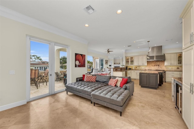 living room featuring ceiling fan, ornamental molding, beverage cooler, and sink