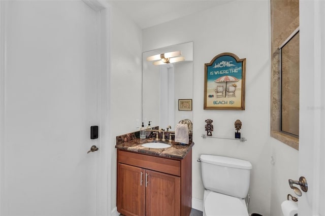 bathroom featuring a shower with door, vanity, and toilet