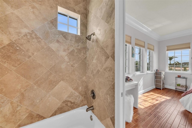 bathroom with ornamental molding and tiled shower / bath