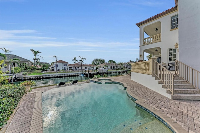 view of pool with a water view, an in ground hot tub, and a patio area