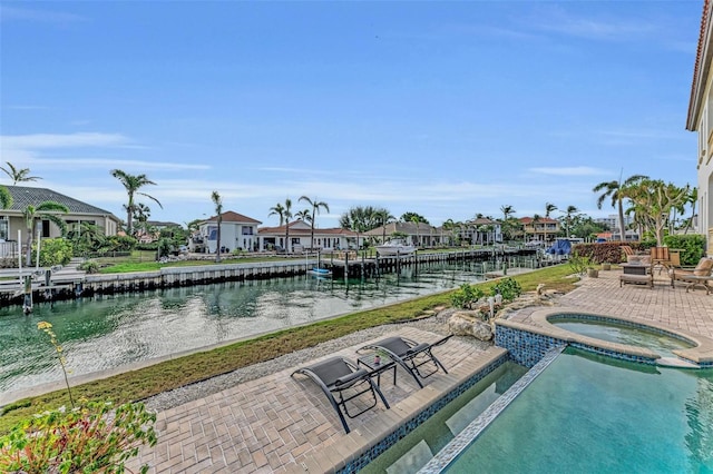 view of pool featuring an in ground hot tub, a water view, and a patio