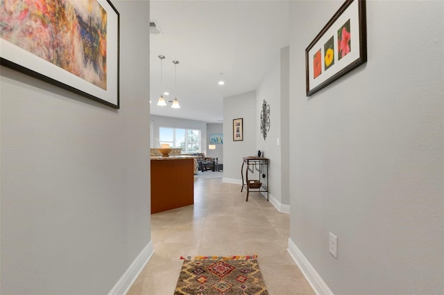 hall featuring light tile patterned floors and a notable chandelier