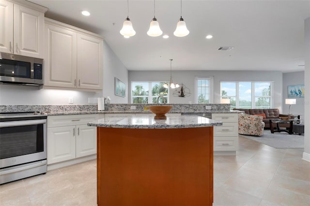 kitchen featuring stainless steel appliances, pendant lighting, a chandelier, and white cabinetry