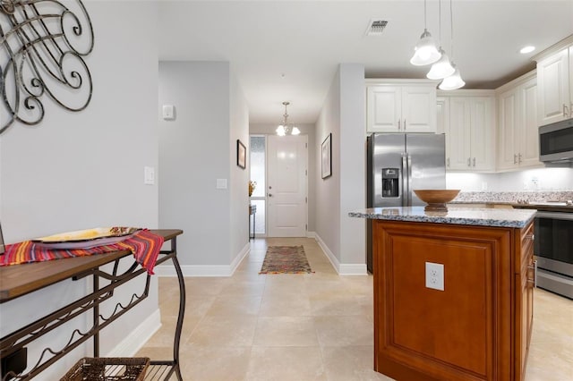 kitchen featuring a center island, pendant lighting, white cabinetry, stainless steel appliances, and light stone counters