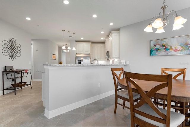 kitchen featuring light stone countertops, white cabinets, decorative light fixtures, stainless steel appliances, and kitchen peninsula