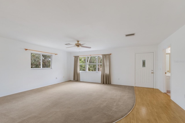 empty room with ceiling fan and light hardwood / wood-style flooring